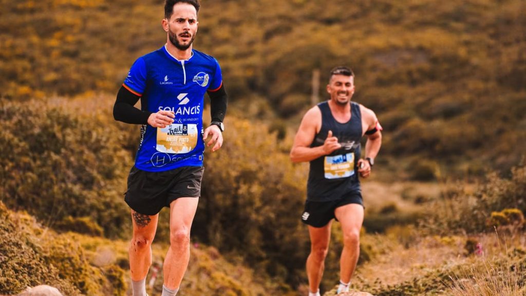 Dynamic image of two men trail running through an outdoor natural setting, showcasing energy and fitness.